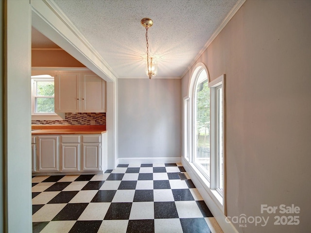 318 Chestnut Ave, Kannapolis, NC 28081 - unfurnished dining area with dark floors, a chandelier, ornamental molding, a textured ceiling, and baseboards