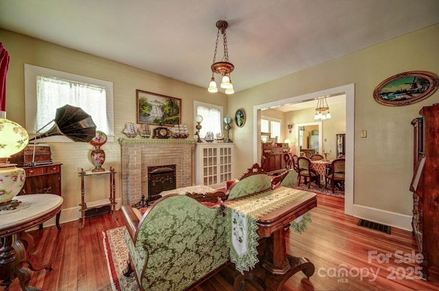 401 7th St, Spencer, NC 28159 - living area featuring wood finished floors, healthy amount of natural light, baseboards, and a brick fireplace