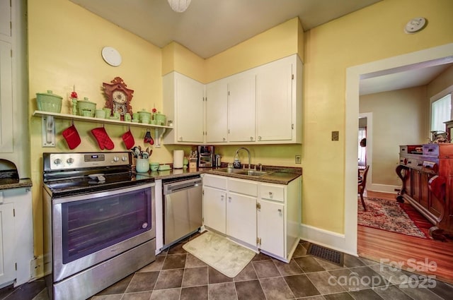 401 7th St, Spencer, NC 28159 - kitchen with appliances with stainless steel finishes, a sink, dark countertops, white cabinetry, and dark tile patterned floors