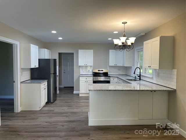 kitchen featuring stainless steel appliances, a sink, a peninsula, recessed lighting, and backsplash