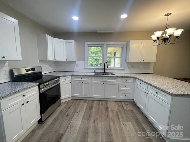 kitchen with stainless steel electric range oven, a sink, a peninsula, light wood-style floors, and white cabinets