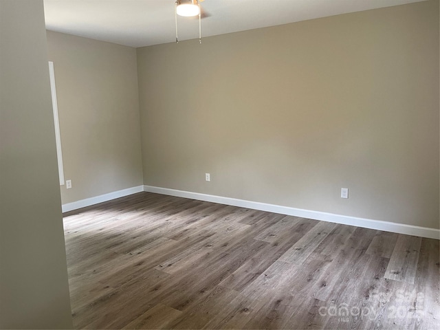spare room featuring dark wood-style floors, ceiling fan, and baseboards