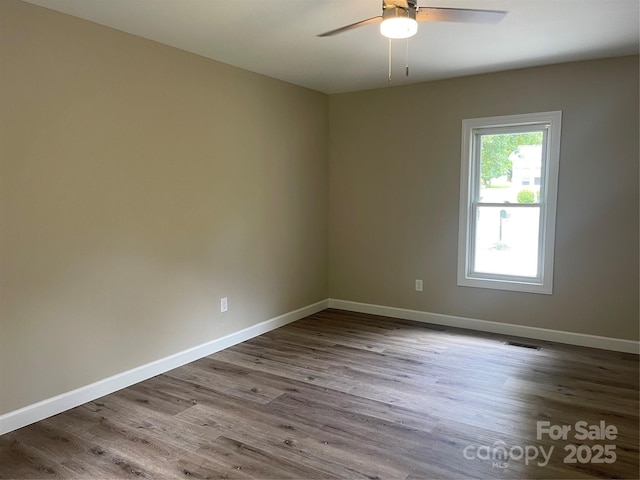 empty room featuring ceiling fan, wood finished floors, and baseboards
