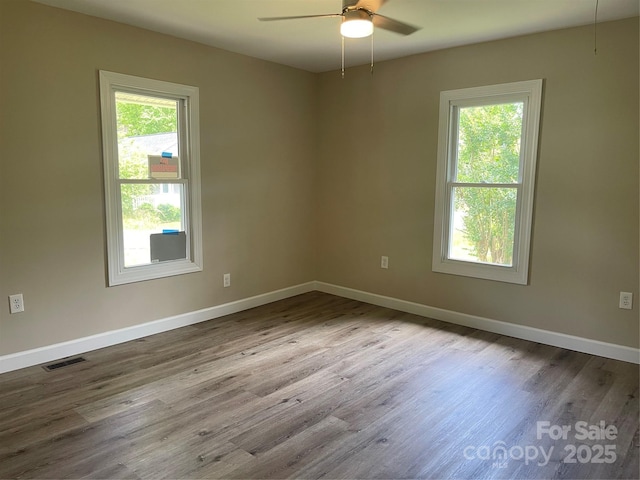 unfurnished room with a ceiling fan, healthy amount of natural light, and wood finished floors