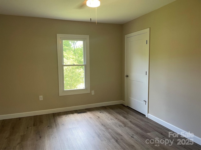 empty room featuring wood finished floors, baseboards, and ceiling fan