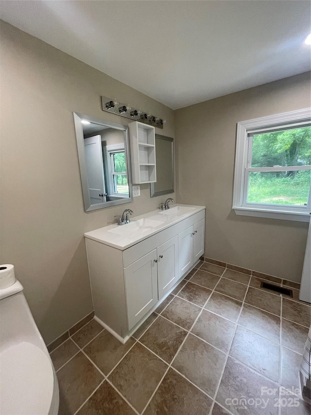 full bath with healthy amount of natural light, double vanity, and baseboards