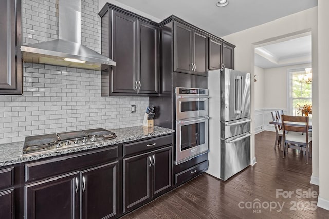 2835 Berkhamstead Cir, Concord, NC 28027 - kitchen featuring appliances with stainless steel finishes, wall chimney exhaust hood, light stone countertops, dark wood-type flooring, and a chandelier