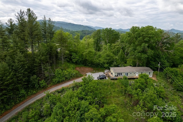 view from above of property with a heavily wooded area and a mountainous background