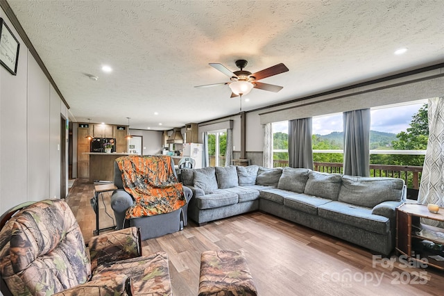 living room with a textured ceiling, ceiling fan, light wood-style floors, and recessed lighting