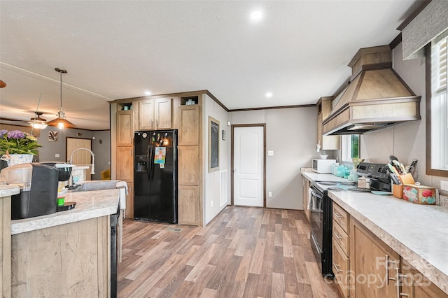 kitchen with black appliances, premium range hood, light wood finished floors, light countertops, and decorative light fixtures