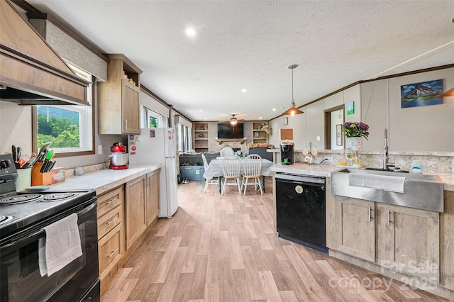 kitchen with black appliances, a sink, light wood-style floors, light countertops, and open floor plan
