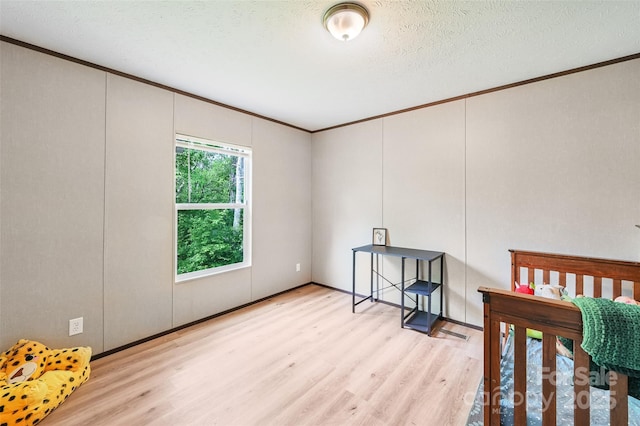 bedroom featuring crown molding, wood finished floors, a decorative wall, and a textured ceiling