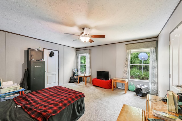 carpeted bedroom featuring crown molding, ceiling fan, a textured ceiling, and a decorative wall