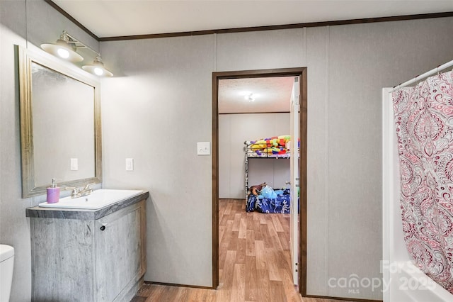 full bathroom featuring wood finished floors, vanity, toilet, crown molding, and shower / tub combo
