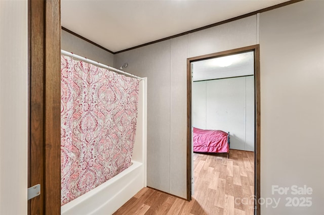 full bathroom featuring wood finished floors, ornamental molding, and shower / tub combo