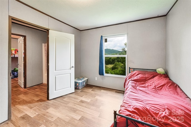 bedroom featuring ornamental molding and light wood-type flooring