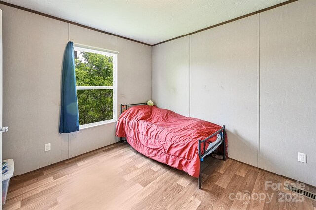 bedroom with wood finished floors and ornamental molding