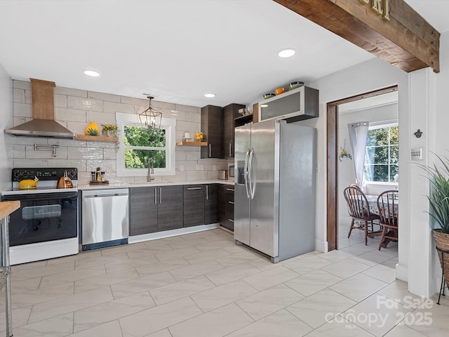 kitchen with stainless steel appliances, open shelves, wall chimney exhaust hood, light countertops, and a sink