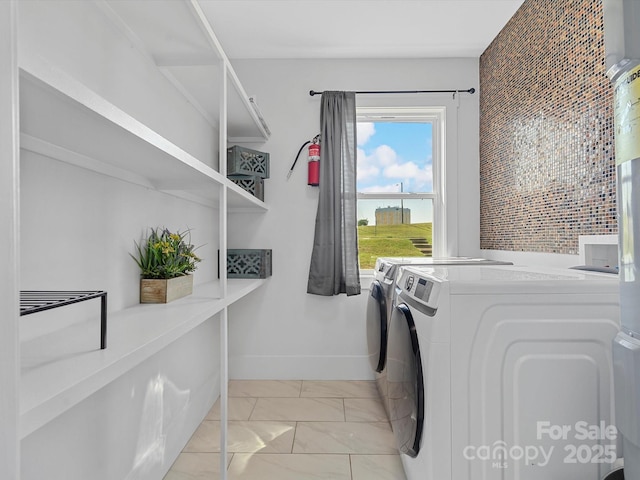 clothes washing area featuring washer and dryer, light marble finish floors, and baseboards