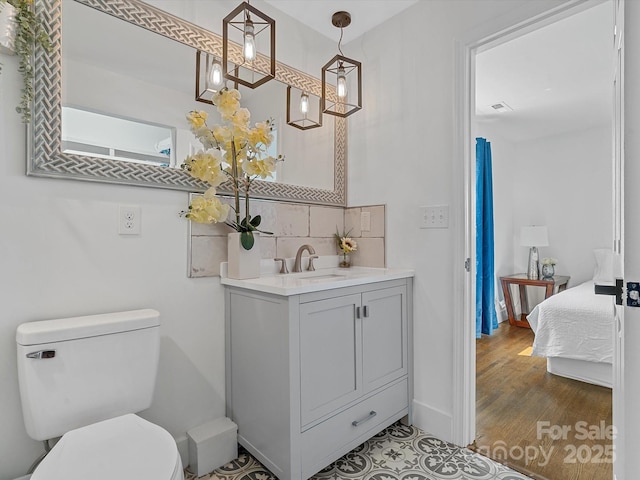 bathroom featuring toilet, tasteful backsplash, vanity, connected bathroom, and baseboards