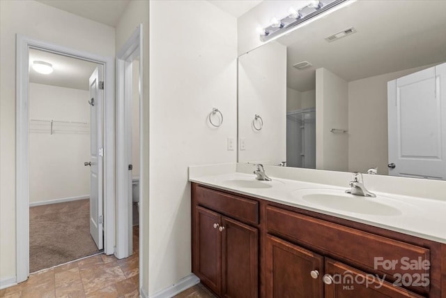 2515 Walnut Forest Dr, Charlotte, NC 28216 - full bathroom with double vanity, stone finish floors, a walk in closet, and baseboards