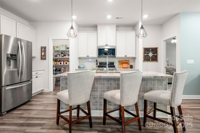 7530 Porrera St, Charlotte, NC 28214 - kitchen with stainless steel appliances, decorative backsplash, wood finished floors, white cabinets, and recessed lighting