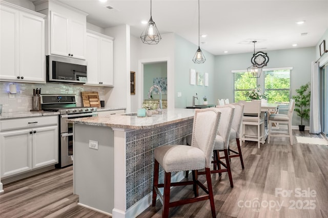 7530 Porrera St, Charlotte, NC 28214 - kitchen with stainless steel appliances, wood finished floors, backsplash, white cabinets, and light stone countertops