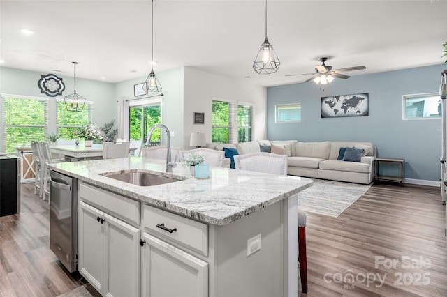 7530 Porrera St, Charlotte, NC 28214 - kitchen with a center island with sink, dishwasher, white cabinets, wood finished floors, and light stone countertops