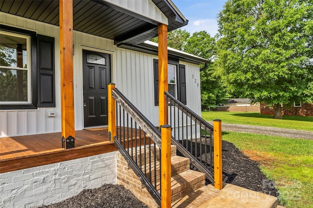 entrance to property with board and batten siding and a yard