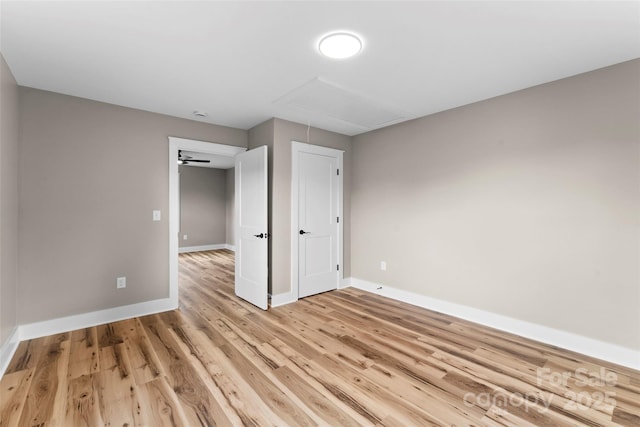 unfurnished bedroom with attic access, baseboards, and light wood-style flooring