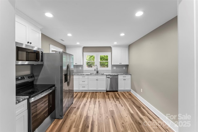 kitchen featuring stainless steel appliances, light wood-style floors, light stone countertops, a sink, and recessed lighting
