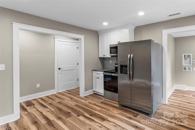 kitchen with stainless steel appliances, white cabinets, light wood-style flooring, recessed lighting, and baseboards