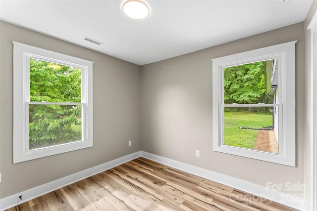 spare room with healthy amount of natural light, baseboards, and light wood-style floors