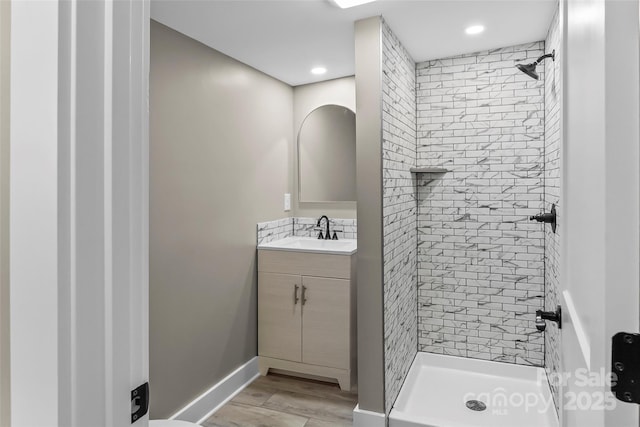bathroom featuring a shower stall, vanity, wood finished floors, recessed lighting, and baseboards