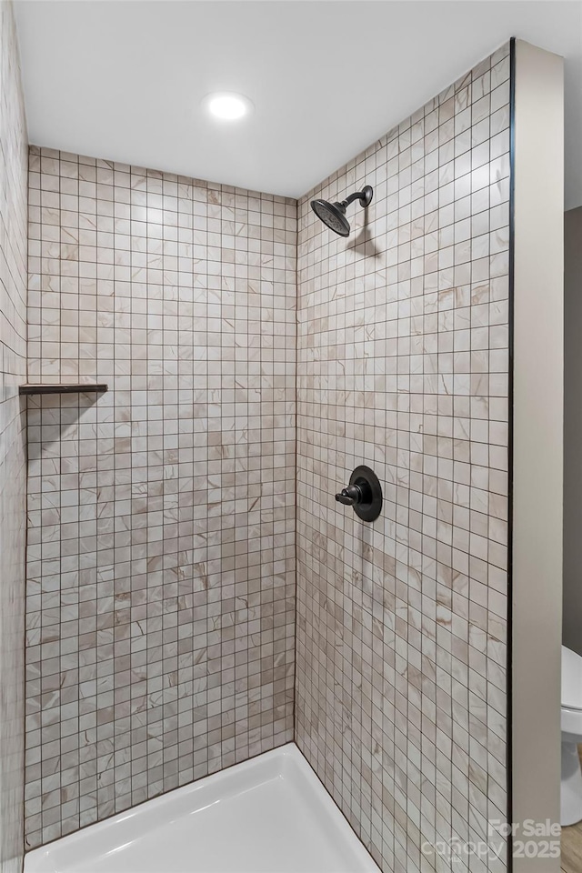 bathroom featuring a tile shower, recessed lighting, and toilet
