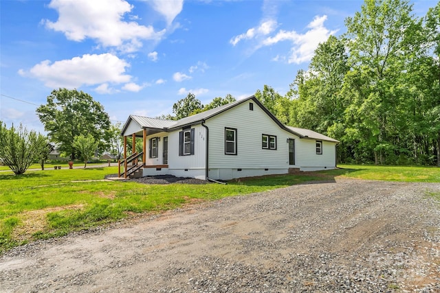 view of front facade featuring crawl space, a front lawn, metal roof, and dirt driveway