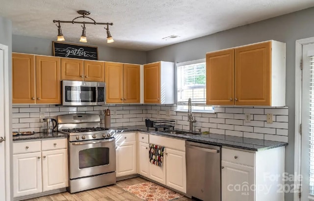 5227 Eagle Creek Dr, Charlotte, NC 28269 - kitchen with appliances with stainless steel finishes, a sink, light wood-style floors, backsplash, and dark stone counters