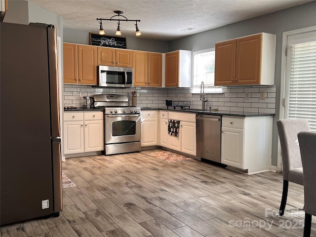 5227 Eagle Creek Dr, Charlotte, NC 28269 - kitchen with appliances with stainless steel finishes, dark countertops, light wood finished floors, tasteful backsplash, and a sink