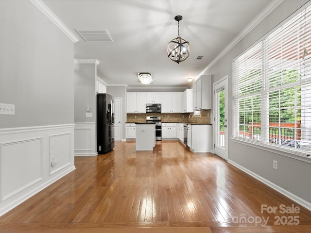 3038 Sterling Ct, Fort Mill, SC 29707 - kitchen with stainless steel appliances, a chandelier, dark countertops, light wood-style flooring, and crown molding