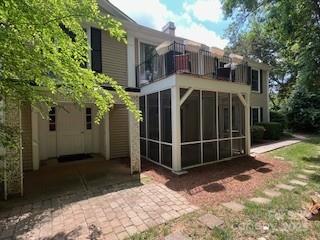 rear view of property featuring a balcony and a sunroom