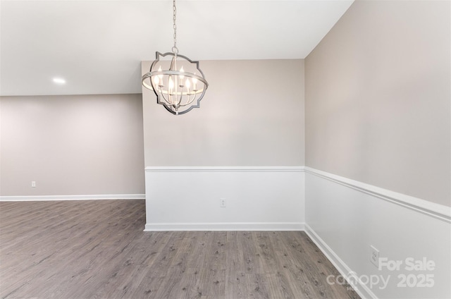 spare room featuring a chandelier, wood finished floors, baseboards, and recessed lighting