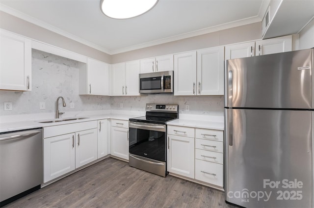 kitchen with stainless steel appliances, a sink, white cabinetry, crown molding, and light countertops