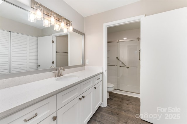 full bathroom featuring toilet, wood finished floors, a stall shower, and vanity