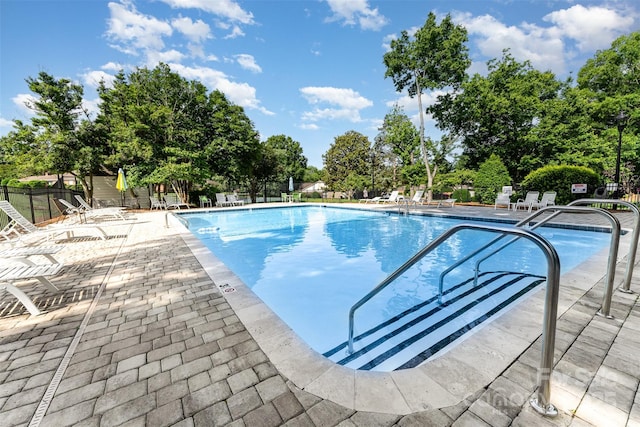 community pool featuring a patio and view of wooded area