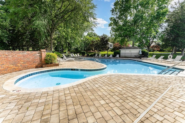 community pool with a patio area and view of scattered trees