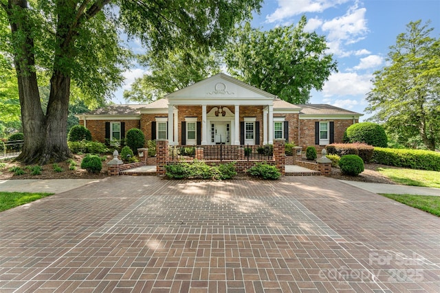 neoclassical / greek revival house featuring covered porch and brick siding
