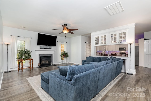 9593 Indian Beech Ave NW, Concord, NC 28027 - living area featuring ceiling fan, a glass covered fireplace, wood finished floors, and baseboards