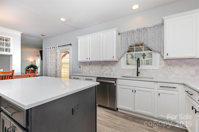 9593 Indian Beech Ave NW, Concord, NC 28027 - kitchen featuring stainless steel dishwasher, a sink, a center island, light wood-type flooring, and decorative backsplash