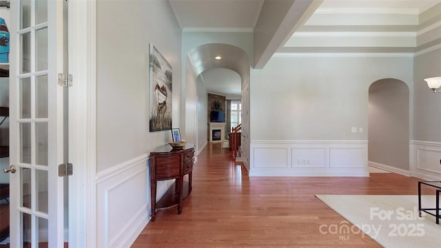 8605 Soaring Eagle Ln, Waxhaw, NC 28173 - hall with arched walkways, wood finished floors, a wainscoted wall, a decorative wall, and crown molding