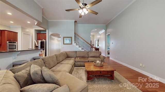 8605 Soaring Eagle Ln, Waxhaw, NC 28173 - living room featuring arched walkways, wood finished floors, stairs, ceiling fan, and crown molding